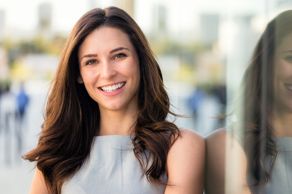A woman smiling confidently outdoors, highlighting the natural and radiant results of teeth whitening – Teeth Whitening in Simi Valley
